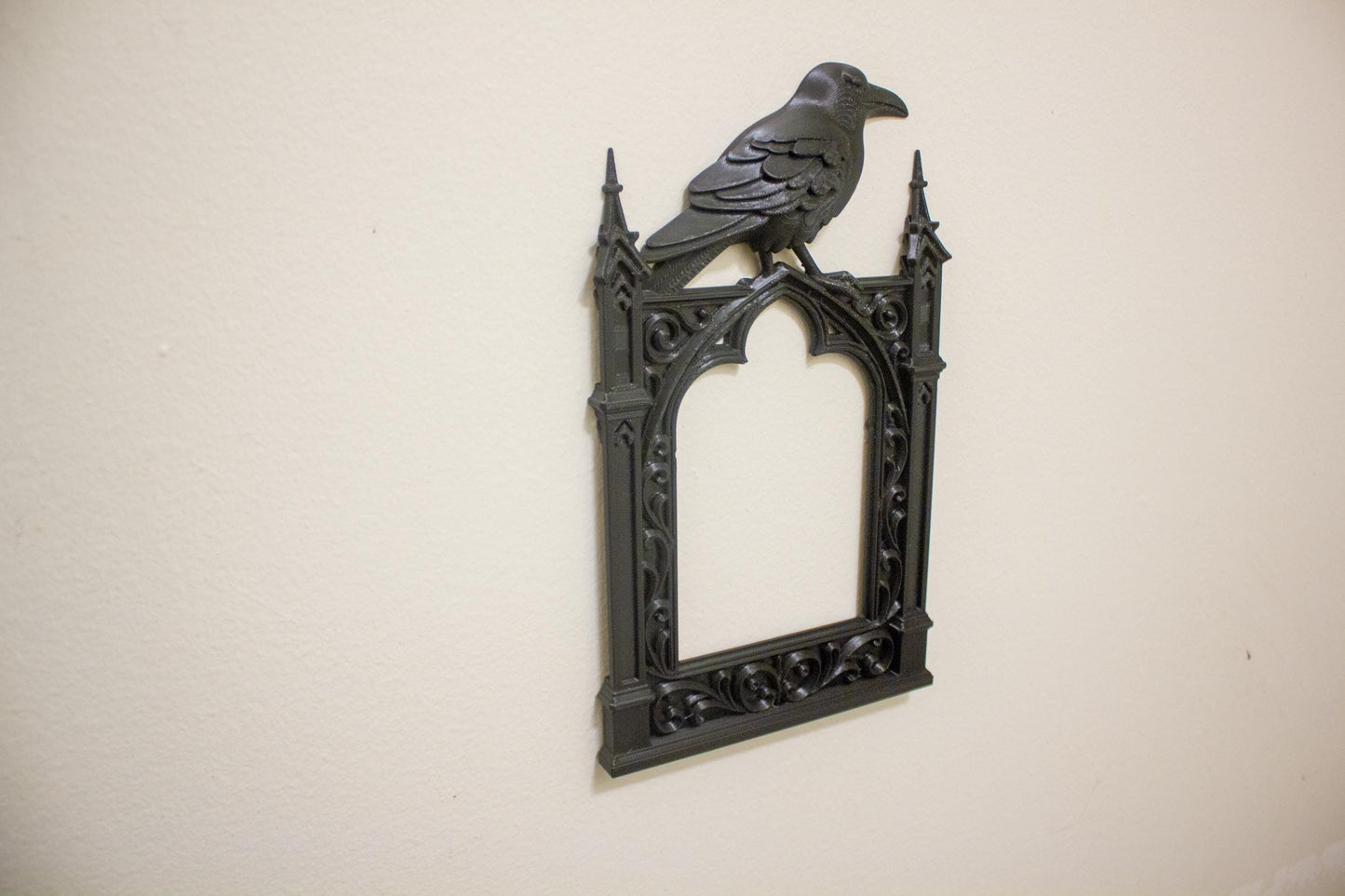 Decorative wall art with a gothic frame and crow on a beige background