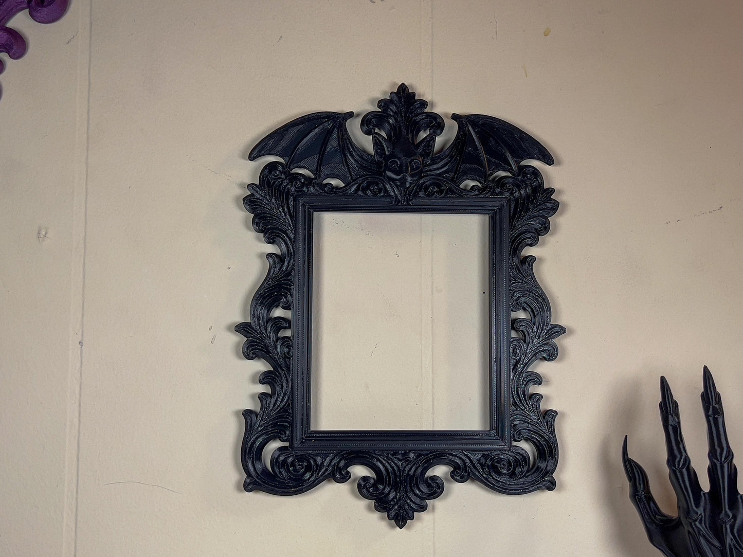 Decorative black frame with intricate designs on a beige wall.