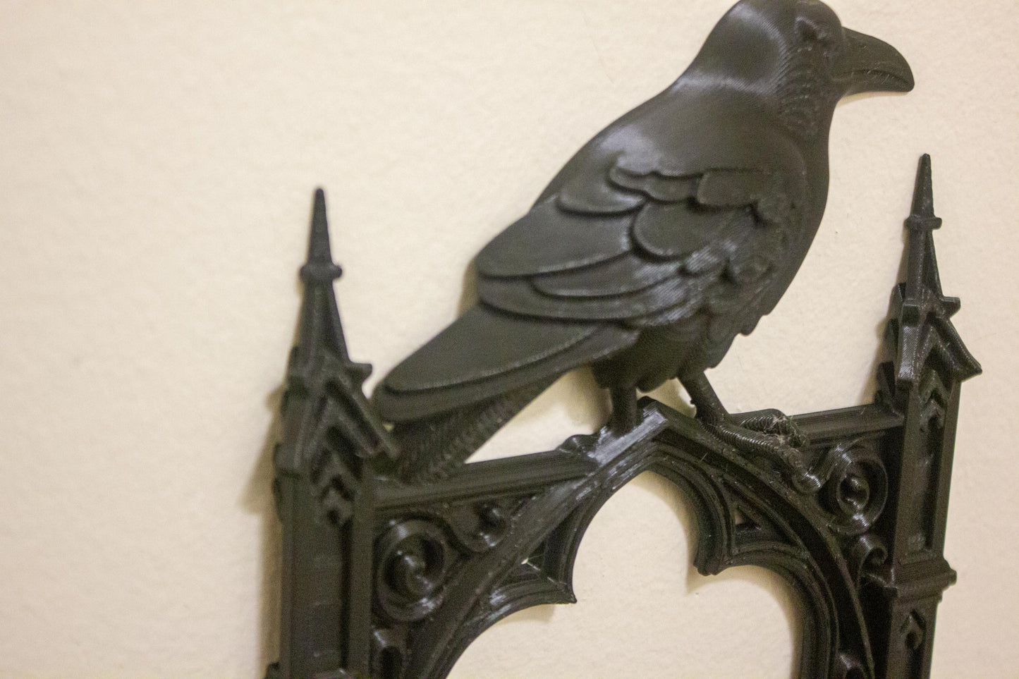 Decorative metal wall piece with a raven design on a beige background