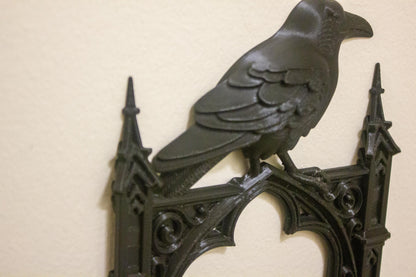 Decorative metal wall piece with a raven design on a beige background