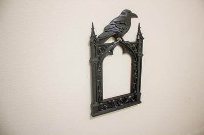 Decorative wall art with a gothic frame and crow on a beige background
