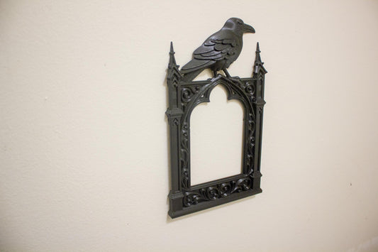 Decorative wall art with a gothic frame and crow on a beige background