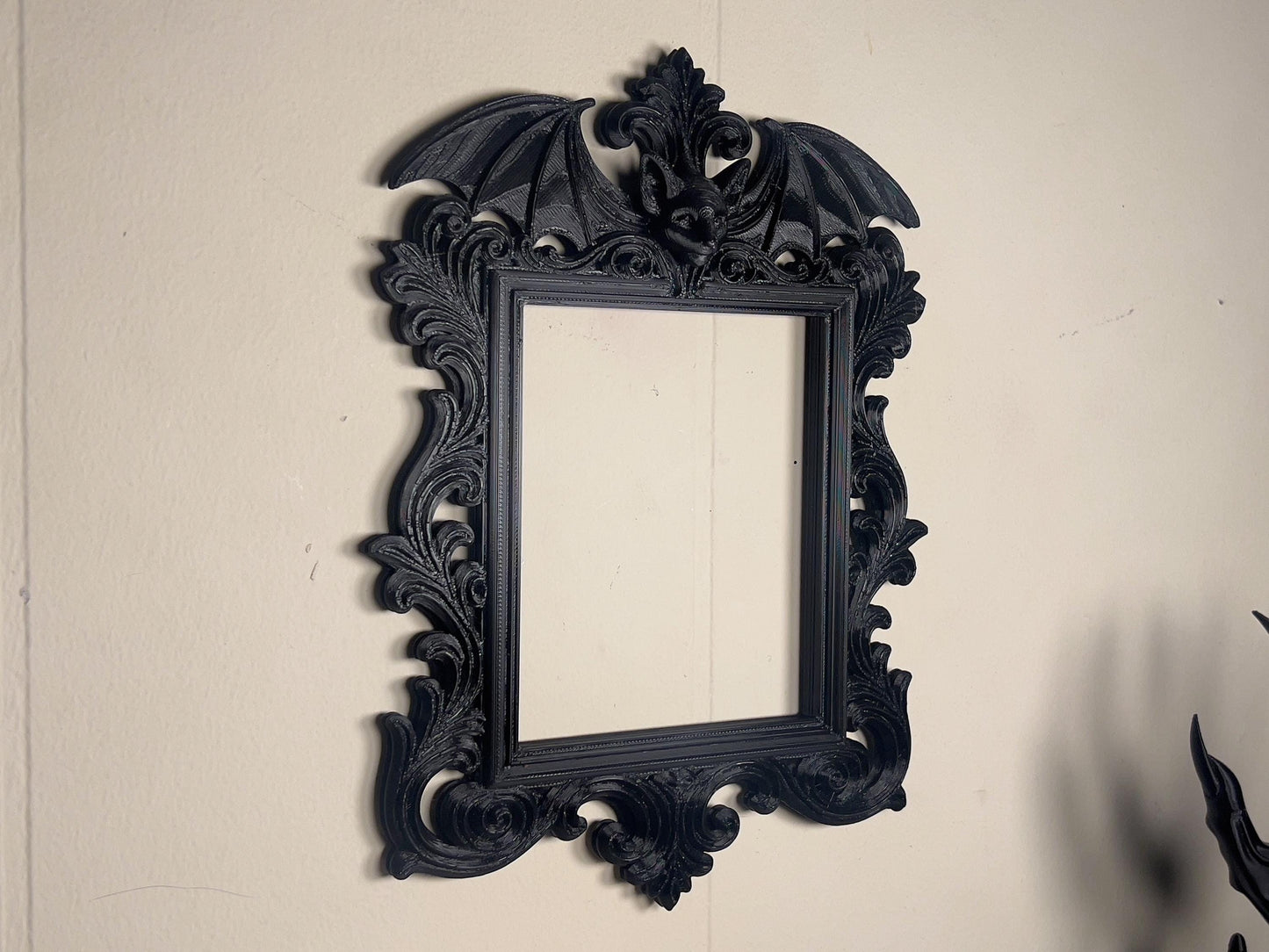 Decorative black frame with bat wings on a plain wall